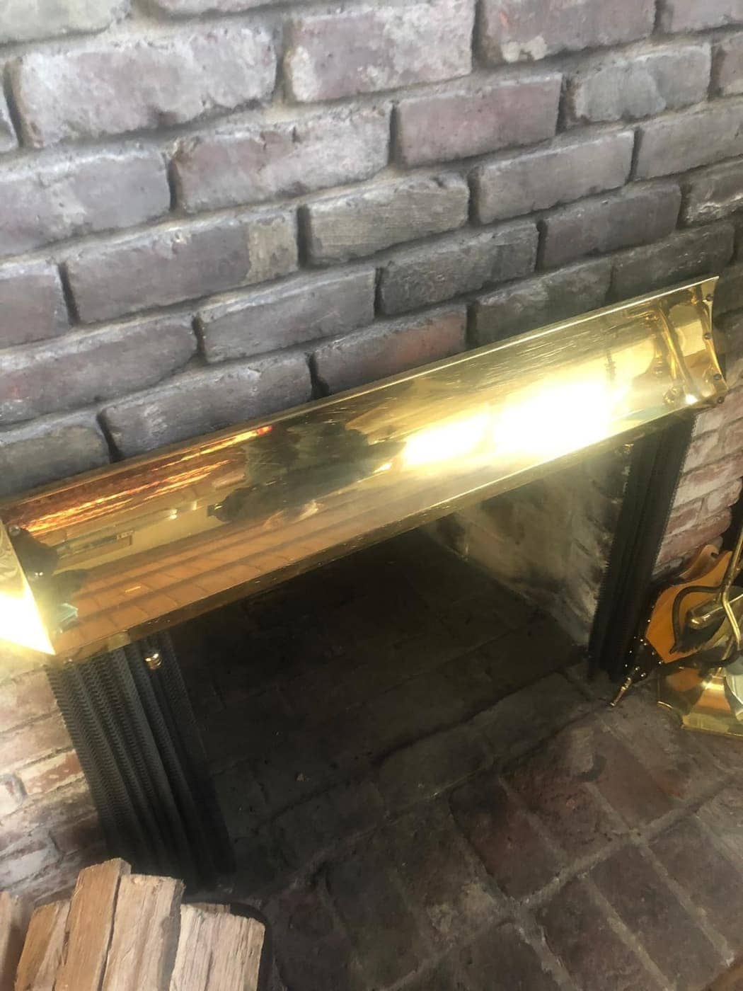A brick fireplace with a brass-trimmed opening and a black frame.