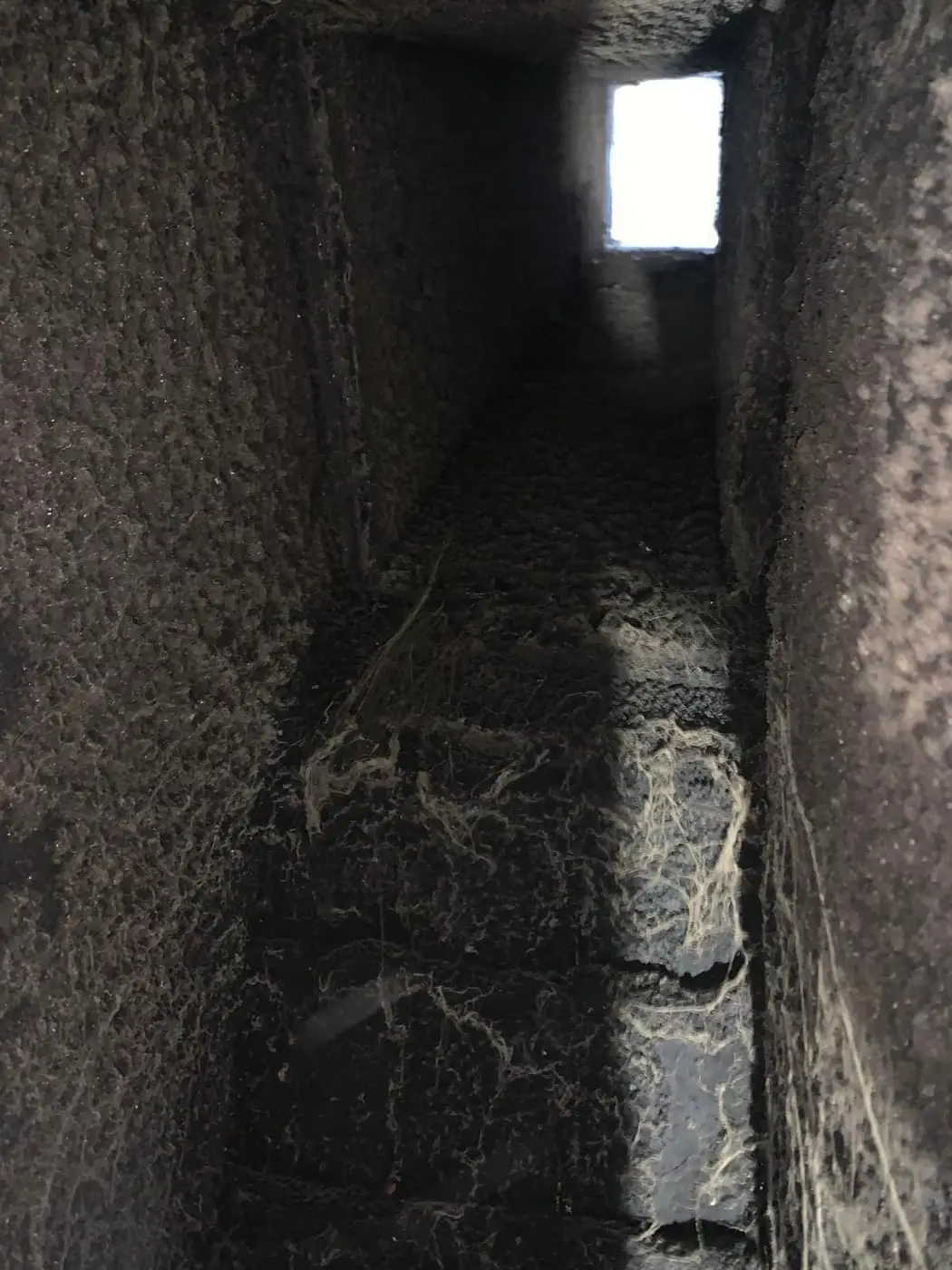 Looking up a soot-lined chimney flue toward the daylight at the top.